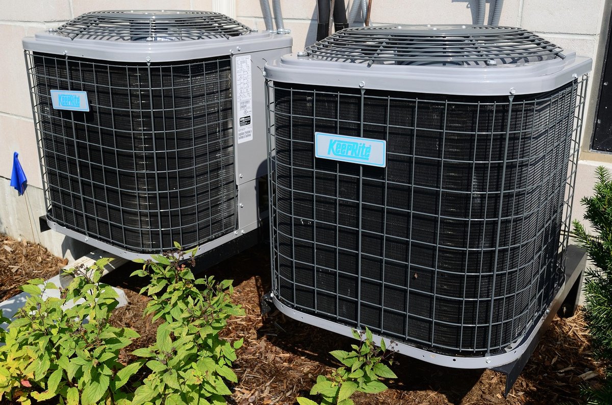 Two residential outdoor AC condensers on a house pad